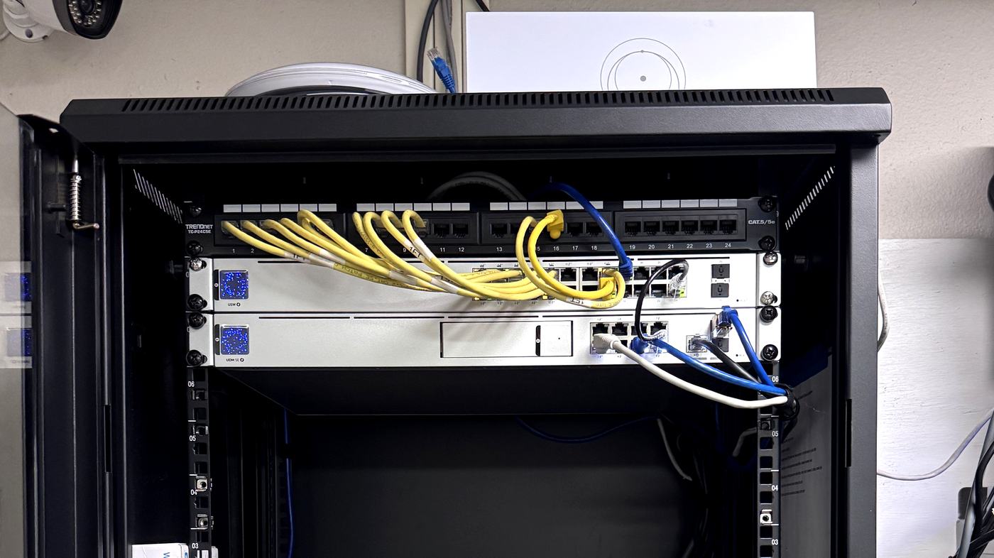 Wall-mounted network cabinet with a labelled Cat5e patch panel, switch and gateway, installed by Allied Technologies